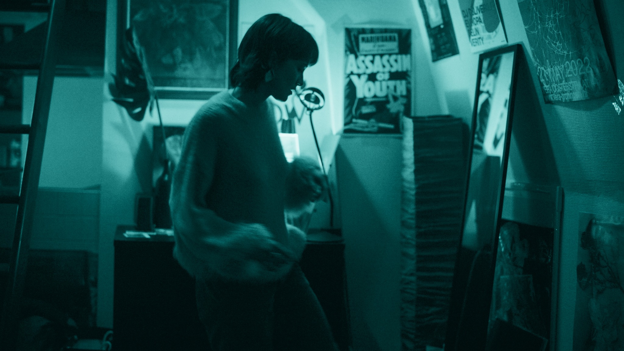 A person getting ready in front of a mirror in a turquoise-lit room